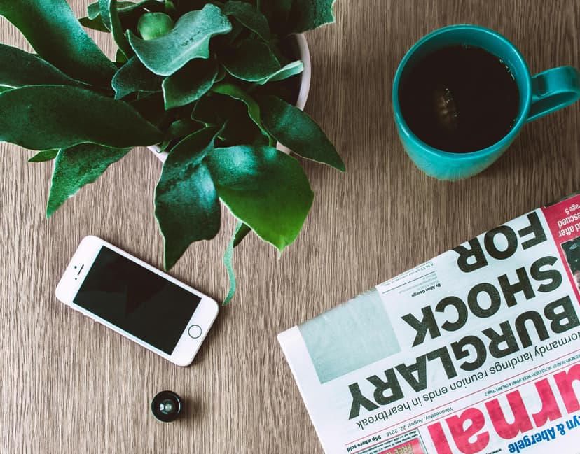 iPhone and newspaper on brown wooden table