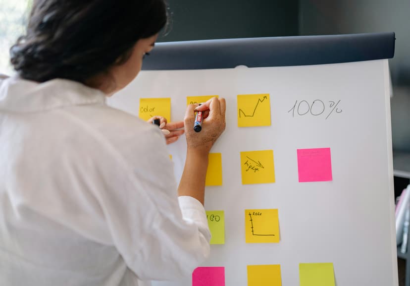 Woman writing on post it notes on whiteboard